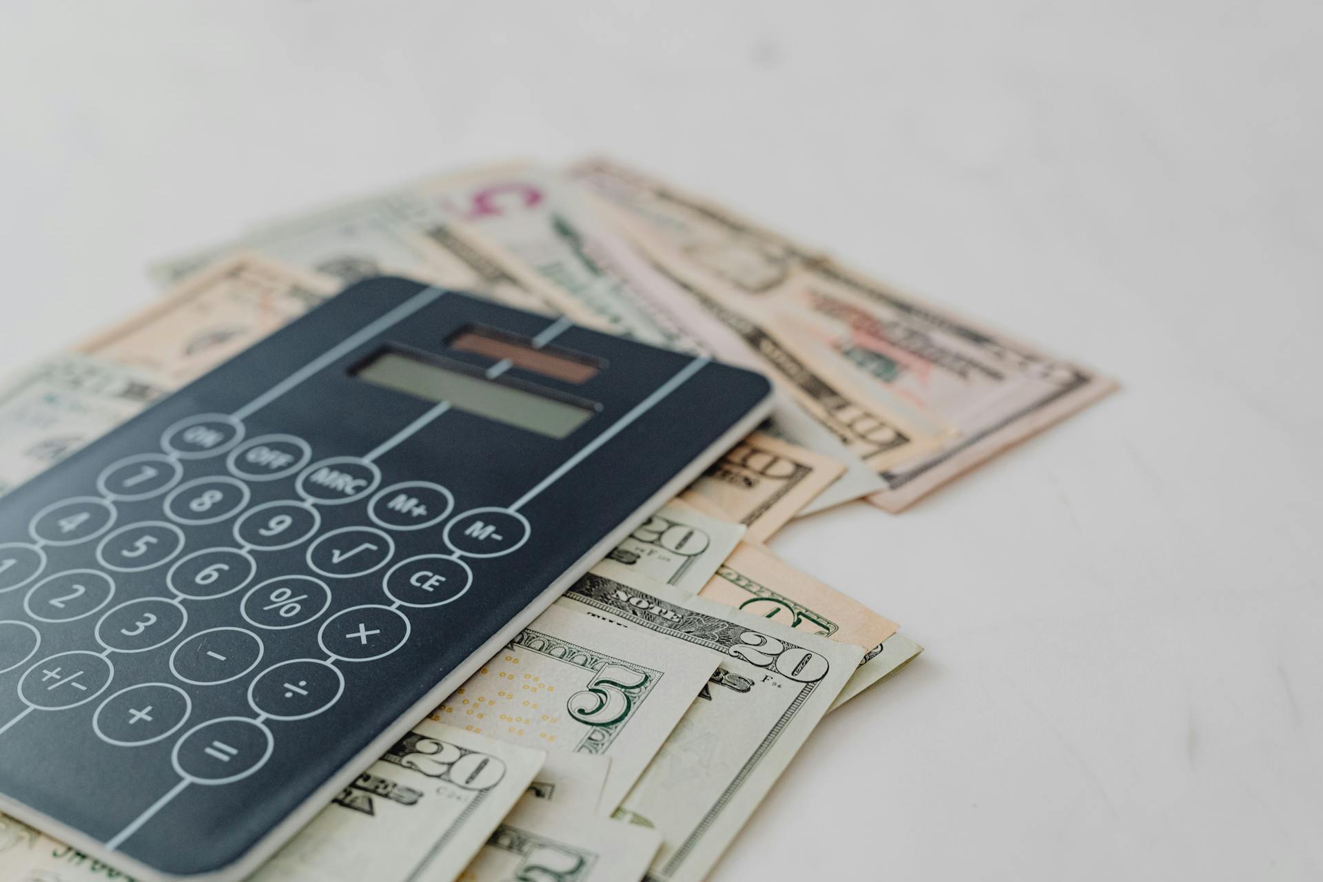 Kalkulator położony na banknotach jako ilustracja tematu jak wycenić dom.